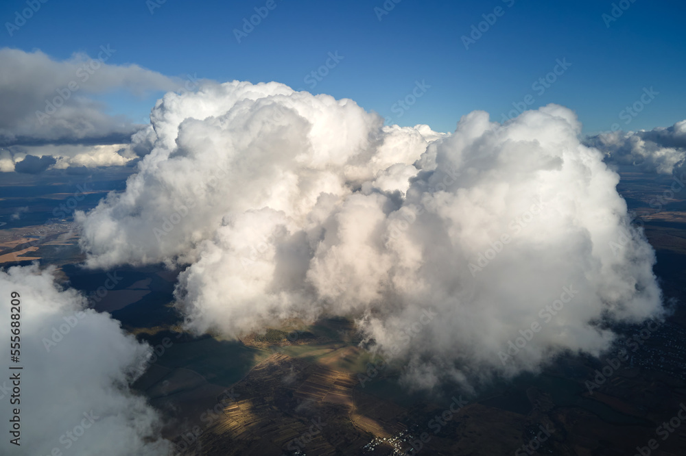 Aerial view at high altitude of earth covered with puffy cumulus clouds forming before rainstorm