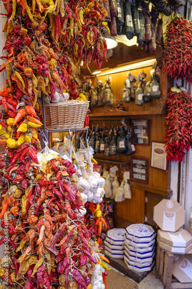 Palma de Mallorca, Spain - 7 Nov, 2022: Strings of red and yellow  chilli peppers hanging in a grocery store
