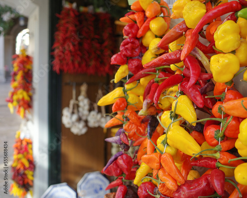 Palma de Mallorca, Spain - 7 Nov, 2022: Strings of red and yellow chilli peppers hanging in a grocery store