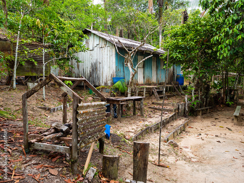 A derelict wood-walled and metal-roofed jungle dwelling and disused work stations once part of an indigenous community in the Amazon rainforest near Manaus, Brazil. 