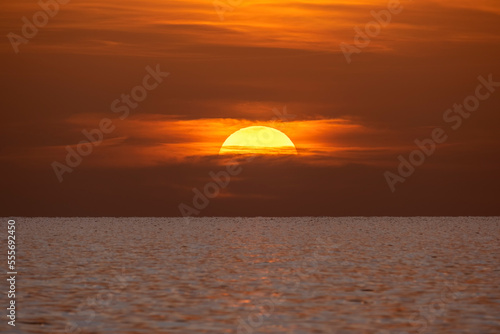 Ocean sunset. Big white sun on dramatic bright sky background, soft evening horizont over sea dark water © bilanol