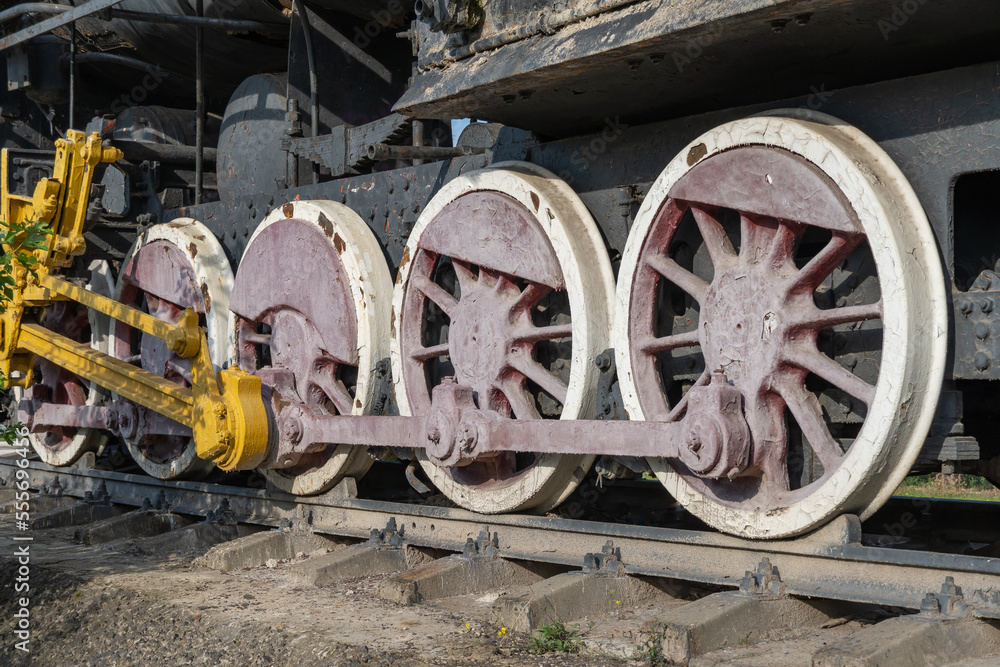 Close-up drive wheels and rods on steam engine locomotive. Vintage part of suspension of old train. Detailes rarity railway transport - lever and chassis, axle and connection. Parts rail.