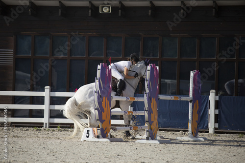 Horse show jumping accident. A rider falling from horse during a competition. Equestrian sport.