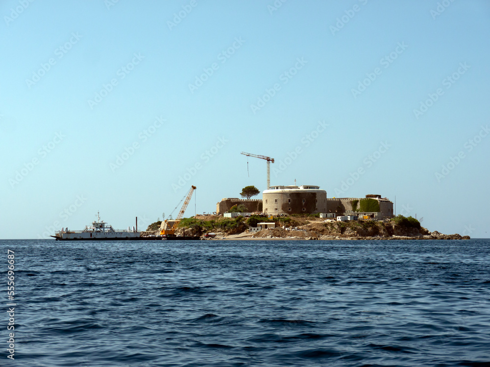 Building construction site on an island with ship and crane view from open water