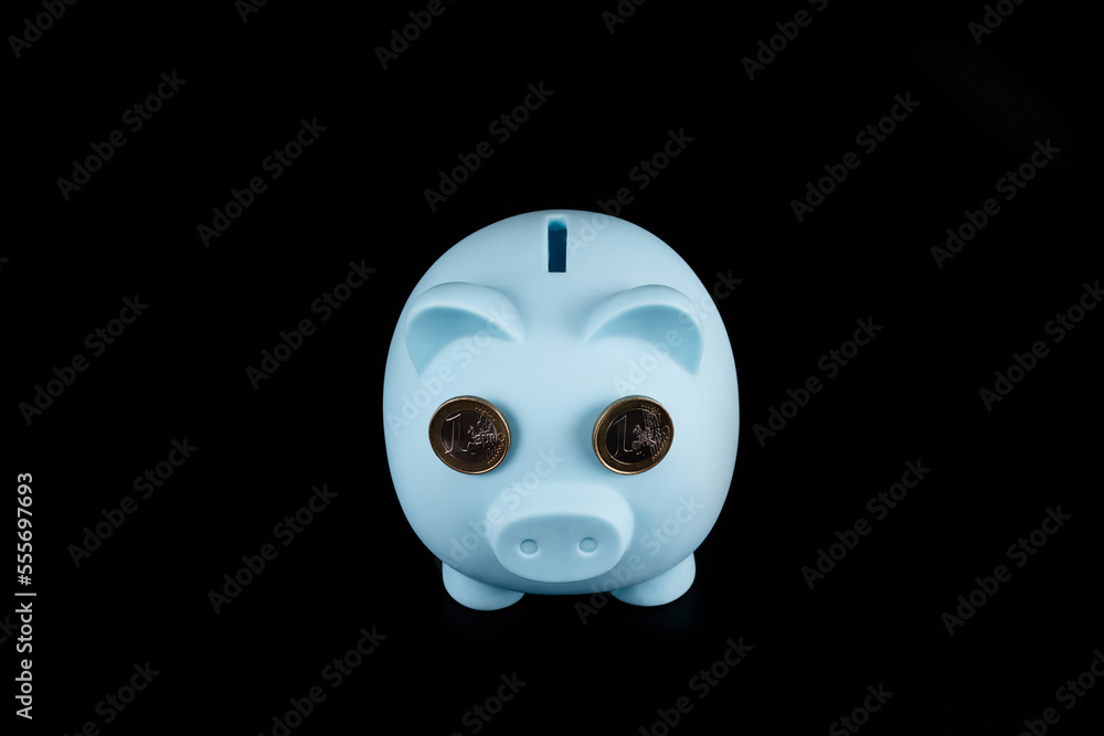 Blue piggy bank with 1 euro coins on a black background Blue piggy bank with 1 euro coins on a black background