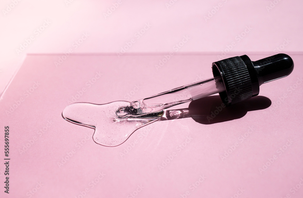 Pipette with facial serum or essential oil in a pastel pink background. Side view, text space. Pipette with facial serum or essential oil in a pastel pink background. Side view, text space.