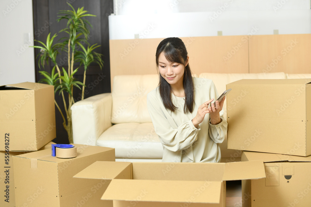 段ボールの前でスマホを持つ若い女性 段ボールの前でスマホを持つ若い女性