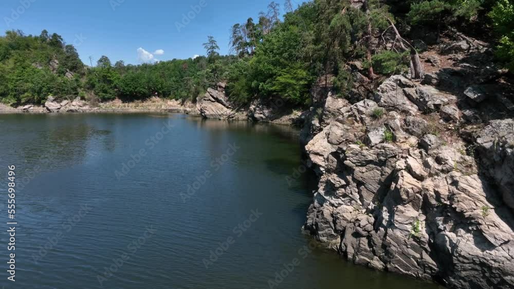 Rocky shore of a flooded dam in the Czech Republic, in the highlands, trees growing on the rocks, around winding river. Rocky shore of a flooded dam in the Czech Republic, in the highlands, trees growing on the rocks, around winding river.