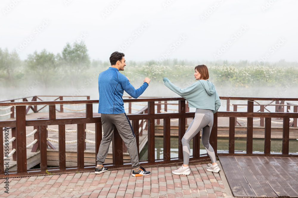 Young sporty couple training on wooden platform on the foggy river Young sporty couple training on wooden platform on the foggy river