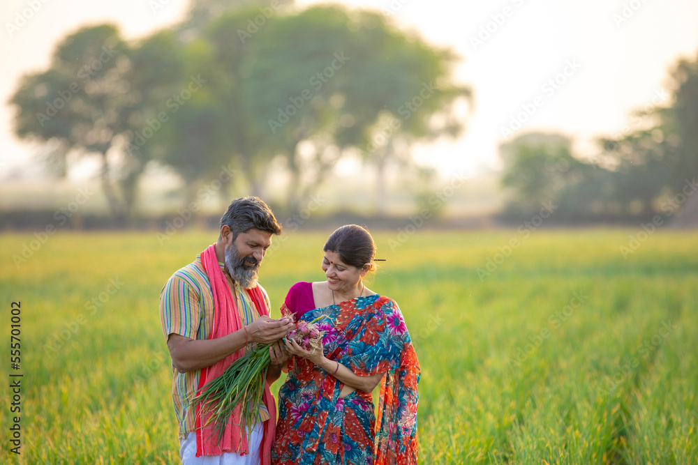 Indian farmer couple holding onion crop and giving happy expression at ...