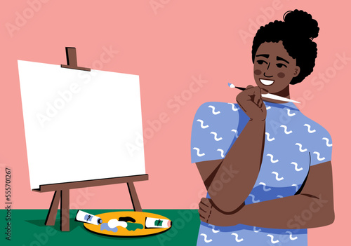 Woman Artist afro at working process. Easel and a blank canvas, oil paints in tubes, palette. Сreative girl thinks what to draw. Fine art hobby