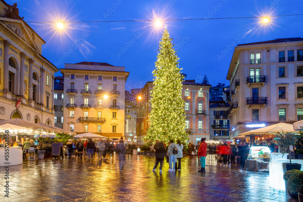 Christmas tree in Lugano - the center of the Reformation Square (Piazza della Riforma). The disco starts (some people dance a little (like me).. Outdoor cafe and  blurred motion of people. 
