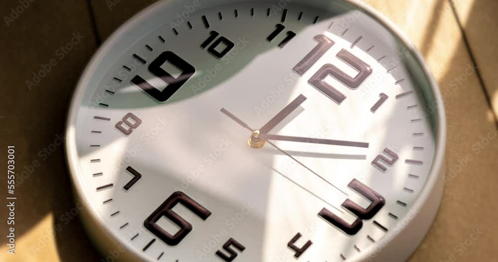 Close-up time lapse of a modern gray wall clock with numerals on the clock face. Selective focus on the number 5 or 5 o'clock. The seconds pointer overtake the minutes frequently. Time passing fast Close-up time lapse of a modern gray wall clock with numerals on the clock face. Selective focus on the number 5 or 5 o'clock. The seconds pointer overtake the minutes frequently. Time passing fast