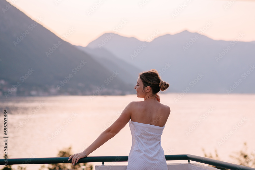 Beautiful young girl model in robe standing on Balcony view on sea shore Kotor, Montenegro.