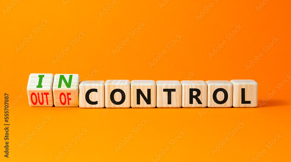 In or out of control symbol. Concept words In control and Out of control on wooden cubes. Beautiful orange table orange background. Business in or out of control concept. Copy space. In or out of control symbol. Concept words In control and Out of control on wooden cubes. Beautiful orange table orange background. Business in or out of control concept. Copy space.