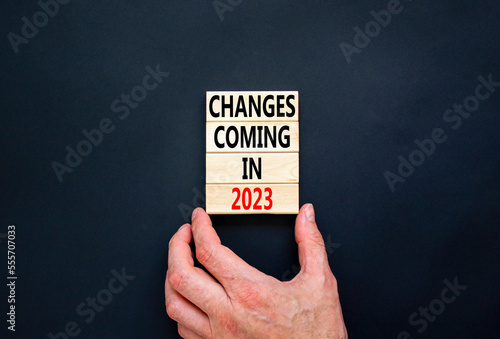 Changes coming in 2023 symbol. Concept word Changes coming in 2023 on wooden blocks. Businessman hand. Beautiful black table black background. Business and changes coming in 2023 concept. Copy space.