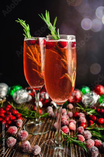 Christmas Mimosas Garnished with Sugared Cranberries and Rosemary: Champagne cocktails made with cranberry juice served in flute glasses