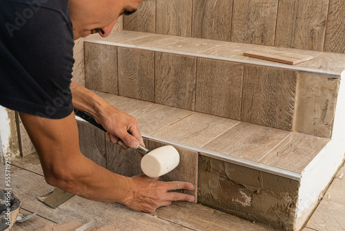 Crop man applying tile on stair