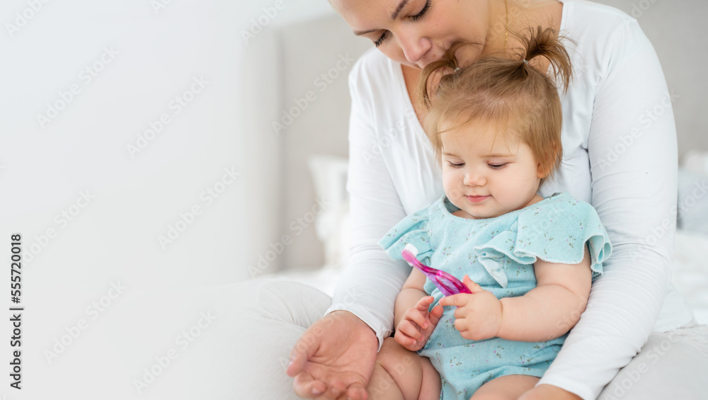 Mother brushing baby's first tooth with toothbrush. Happy healthy lifestyle and baby care. Babyhood and parenthood. Copy space for advertisement Mother brushing baby's first tooth with toothbrush. Happy healthy lifestyle and baby care. Babyhood and parenthood. Copy space for advertisement