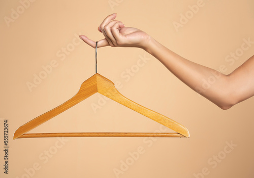 Woman finger holding empty hanger on a beige studio background photo
