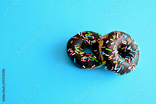 chocolate donuts with sugar sprinkles isolated in blue background, close-up
