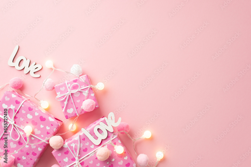 Saint Valentine's Day concept. Top view photo of present boxes light bulb garland inscriptions love and fluffy pompons on isolated pastel pink background with copyspace