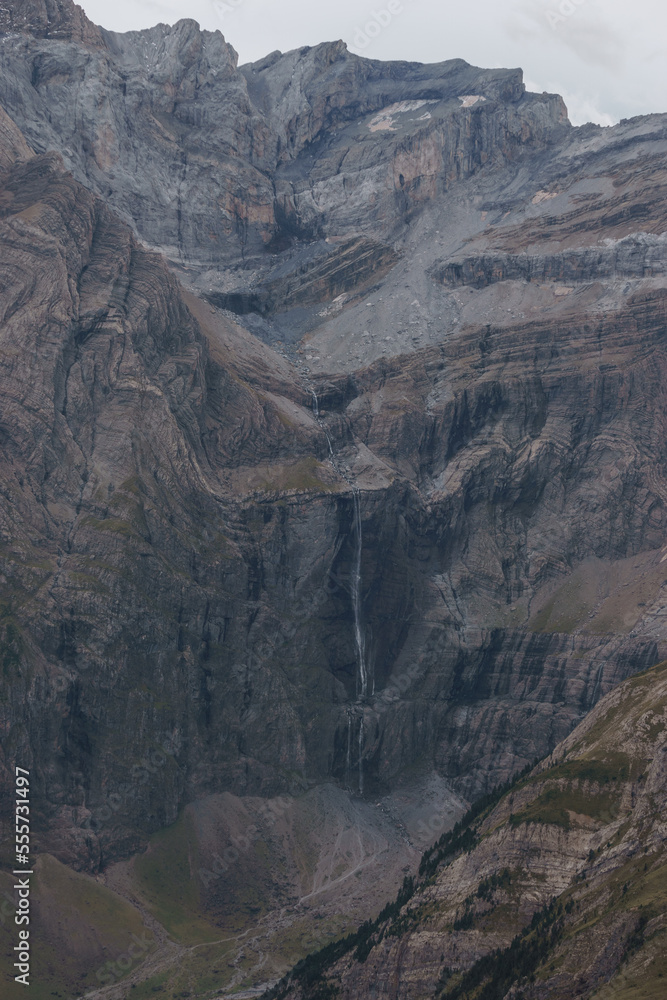 Distant detail view at famous Gavarnie waterfalls in french Pyrenees in extreme terrain with massive rock wall formation, Nouvelle-Aquitaine, France