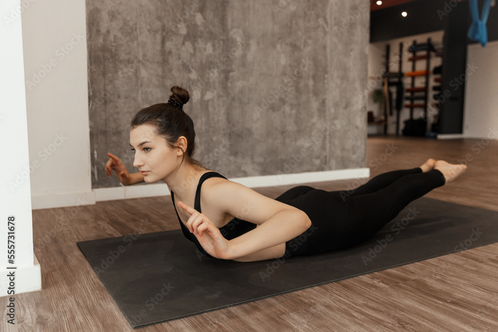 Obraz premium Fit young woman in sportswear doing shoulder and arm stretching exercise 