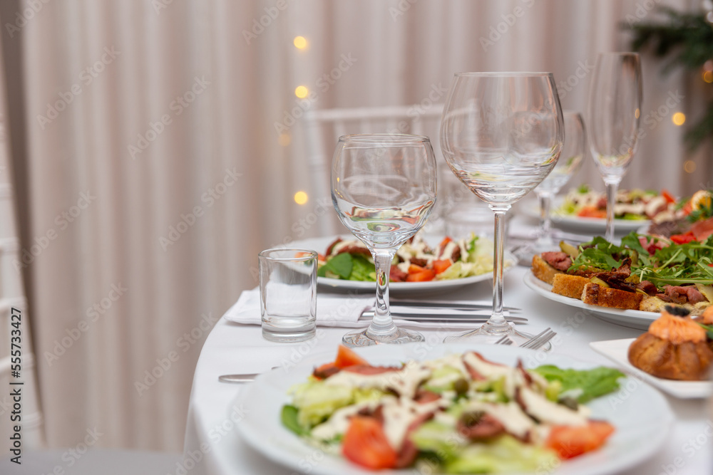 Served for holiday banquet restaurant table with dishes, snack, cutlery, wine and water glasses. Served for holiday banquet restaurant table with dishes, snack, cutlery, wine and water glasses.