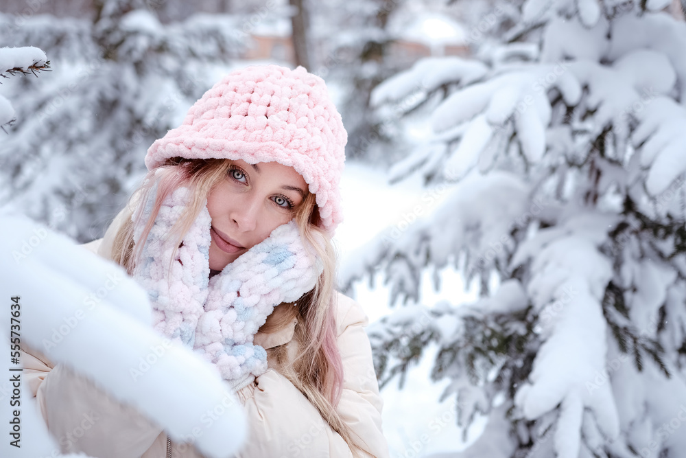 Winter woman in snow looking at camera outside on snowing cold winter day. Portrait Caucasian female model outside in first snow