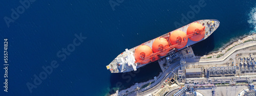 Obraz na płótnie Aerial drone top down ultra wide panoramic photo of LNG (Liquified Natural Gas) tanker anchored in small gas terminal island with tanks for storage w salonie