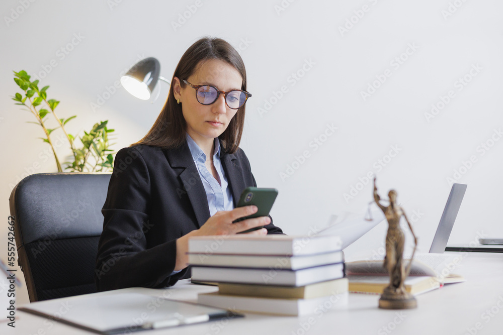 female lawyer in strict suit works in office or court, checks clients' contracts, chats by phone. Caucasian successful business lady, statuette of Themis, goddess of justice. legal advice online. female lawyer in strict suit works in office or court, checks clients' contracts, chats by phone. Caucasian successful business lady, statuette of Themis, goddess of justice. legal advice online.