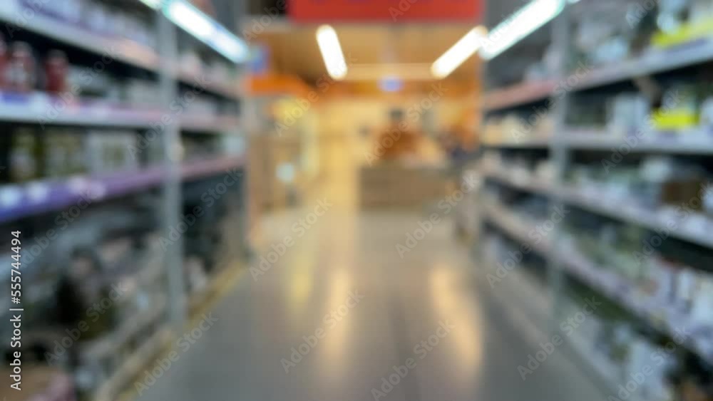 Blurred background when walking through the supermarket. Blurred background of a supermarket interior with shelves from up to the ceiling. Hall or mall with blurred lights background Blurred background when walking through the supermarket. Blurred background of a supermarket interior with shelves from up to the ceiling. Hall or mall with blurred lights background