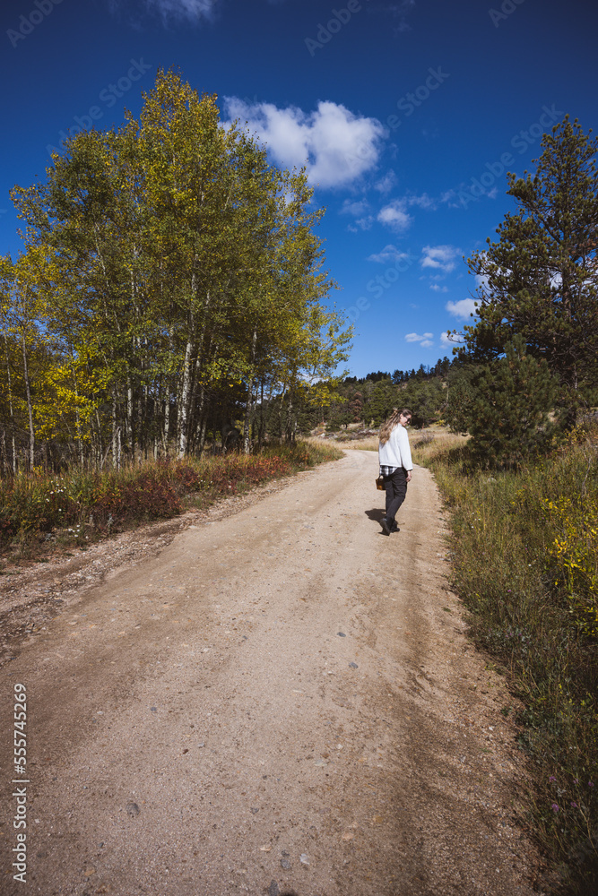 Woman walking on a dirt road holding a basket wearing a white sweater in Boulder county, Colorado - Colorado Rocky Mountain fall winter travel Woman walking on a dirt road holding a basket wearing a white sweater in Boulder county, Colorado - Colorado Rocky Mountain fall winter travel