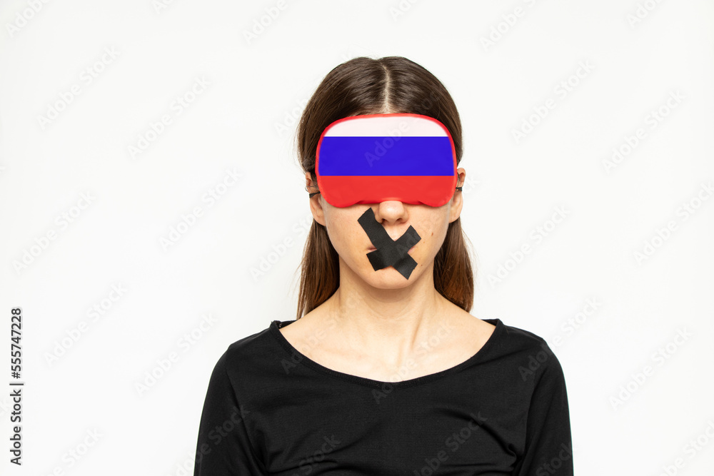 A girl with a blindfold in the color of the flag of Russia and a band-aid closed her mouth on a white background, a Russian girl does not see or hear, a deaf and dumb A girl with a blindfold in the color of the flag of Russia and a band-aid closed her mouth on a white background, a Russian girl does not see or hear, a deaf and dumb