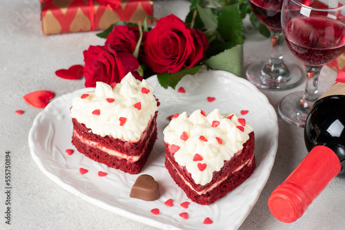 Cakes Red velvet in the shape of hearts on white plate, roses and wine for Valentines Day