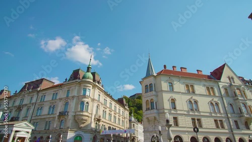 Historical buildings with pointed towers on roofs stand on square with vintage street lanterns under clear blue sky in Ljubljana Slovenia photo