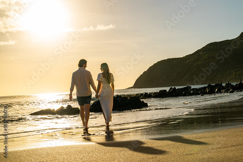 Picturesque romantic couple walking on an empty tropical beach during the sunset on a remote island