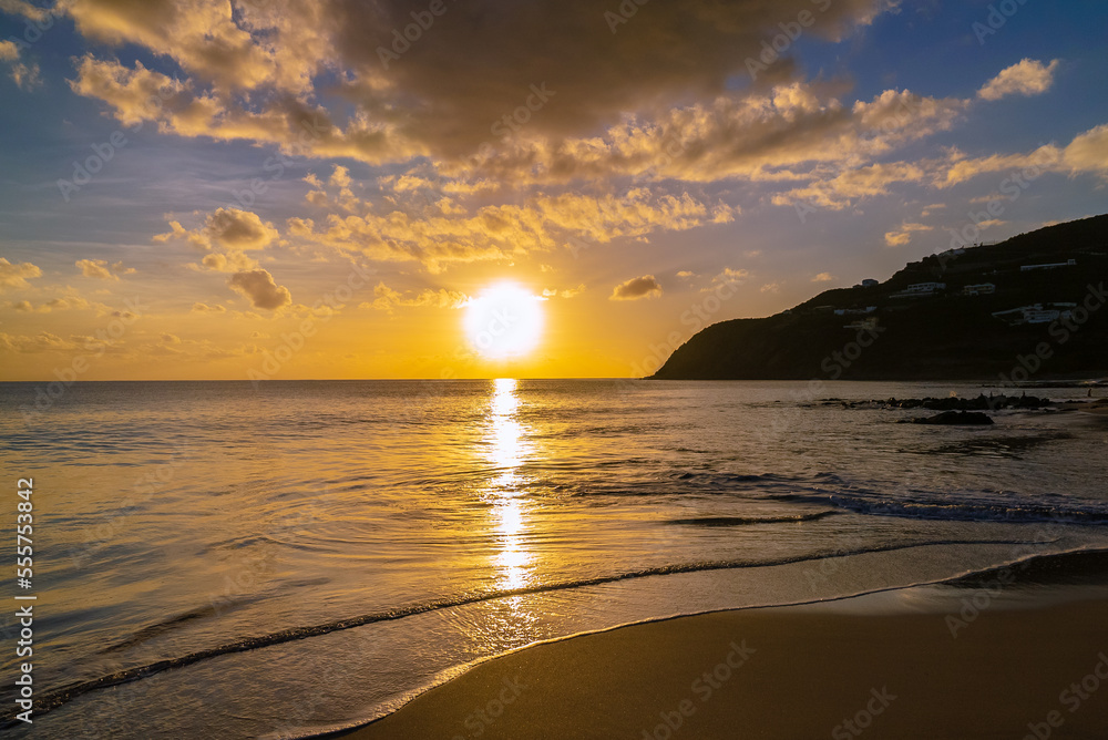 Picturesque golden sunset on an emtpy sandy beach on a tropical island