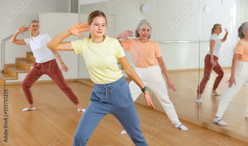 Young girl performing aerobic dance during group training with her mother and grandmother.