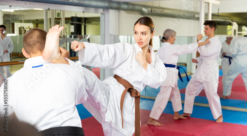 Man and woman in kimono sparring together in gym during karate training