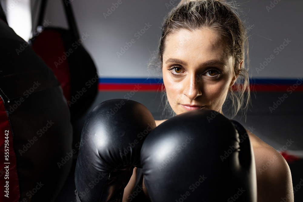 Portrait of caucasian sports woman with boxing bag at gym