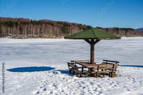Winter landscape by the frozen lake with hills in the background background. Frozen Lake on a cold winter day © Bojan