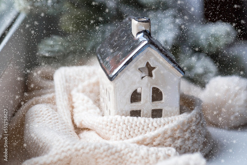 A house wrapped in a scarf. Winter. Home insulation, protection from cold and bad weather, room heating system. The energy crisis in Europe. Festive mood, Christmas, New Year 2023