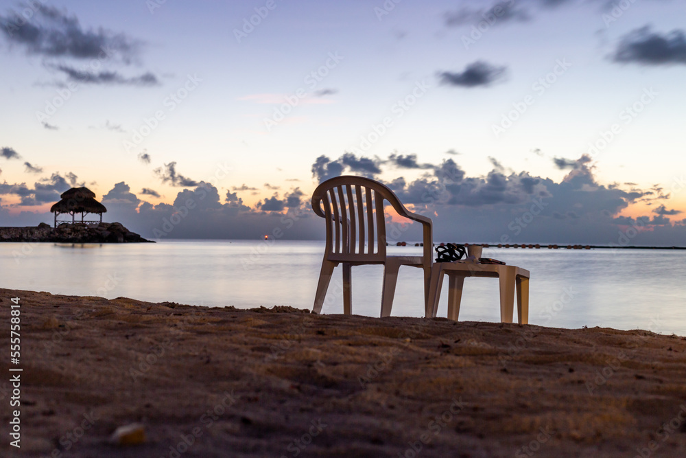 chaise en plastique et tabouret sur la plage en bord de mer lors d'un lever de soleil