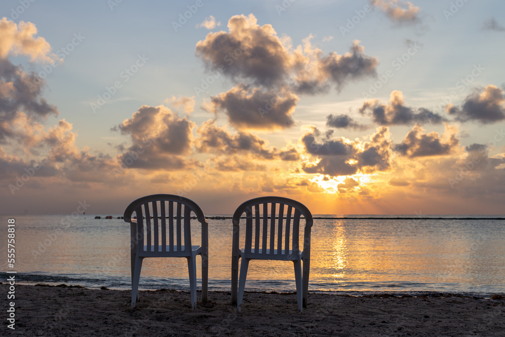 pair de chaises en plastique sur la plage avec vue sur la mer lors d'un lever de soleil
