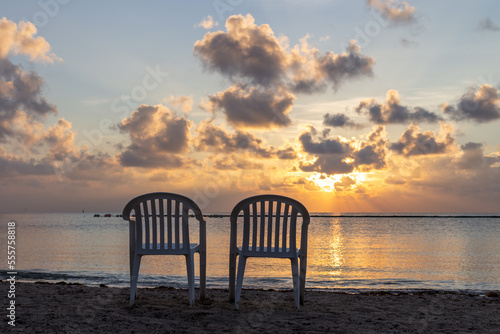 pair de chaises en plastique sur la plage avec vue sur la mer lors d'un lever de soleil