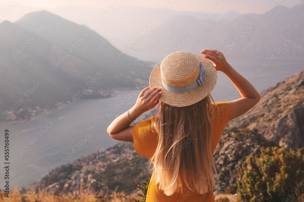 Rear view of young woman in straw hat, who looking from above to the Kotor city and Boka bay, Montenegro.