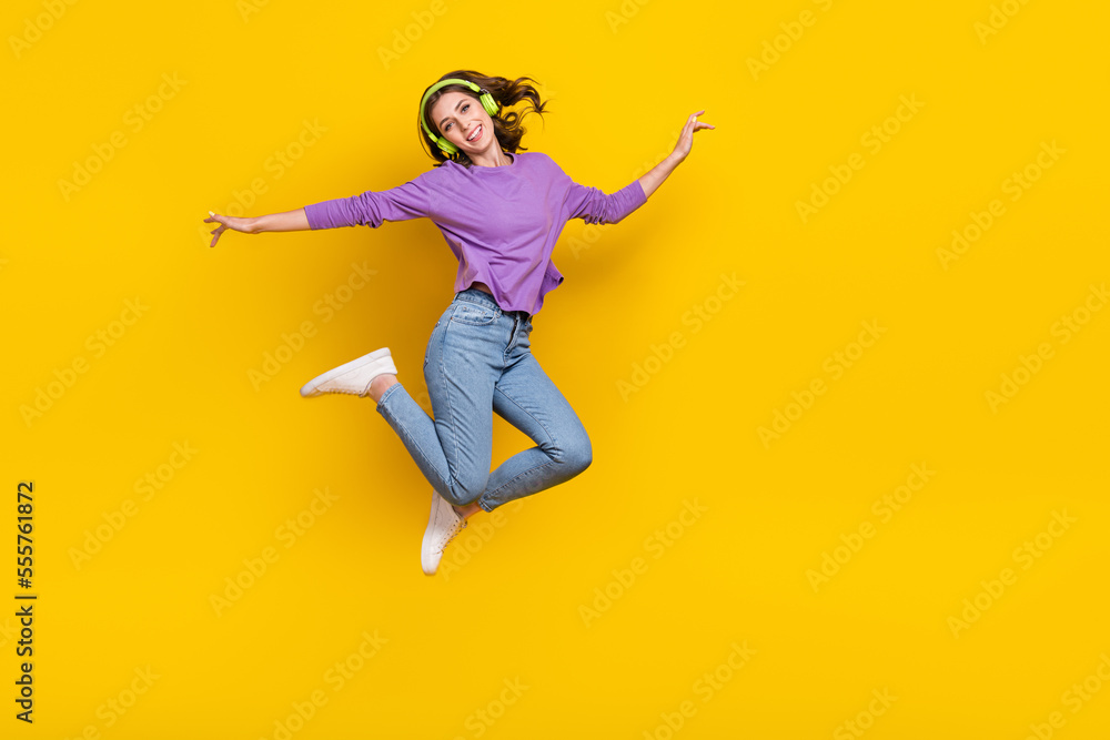 Full body photo of excited carefree lady jumping listen music empty space isolated on yellow color background