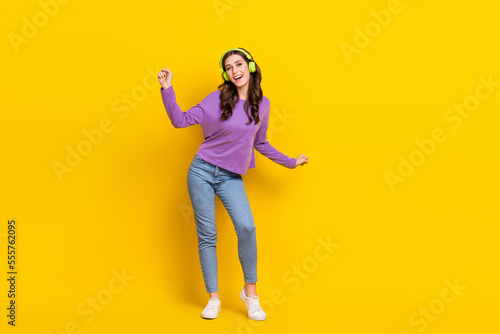 Full body portrait of overjoyed cheerful lady have fun dancing listen new single isolated on yellow color background © deagreez